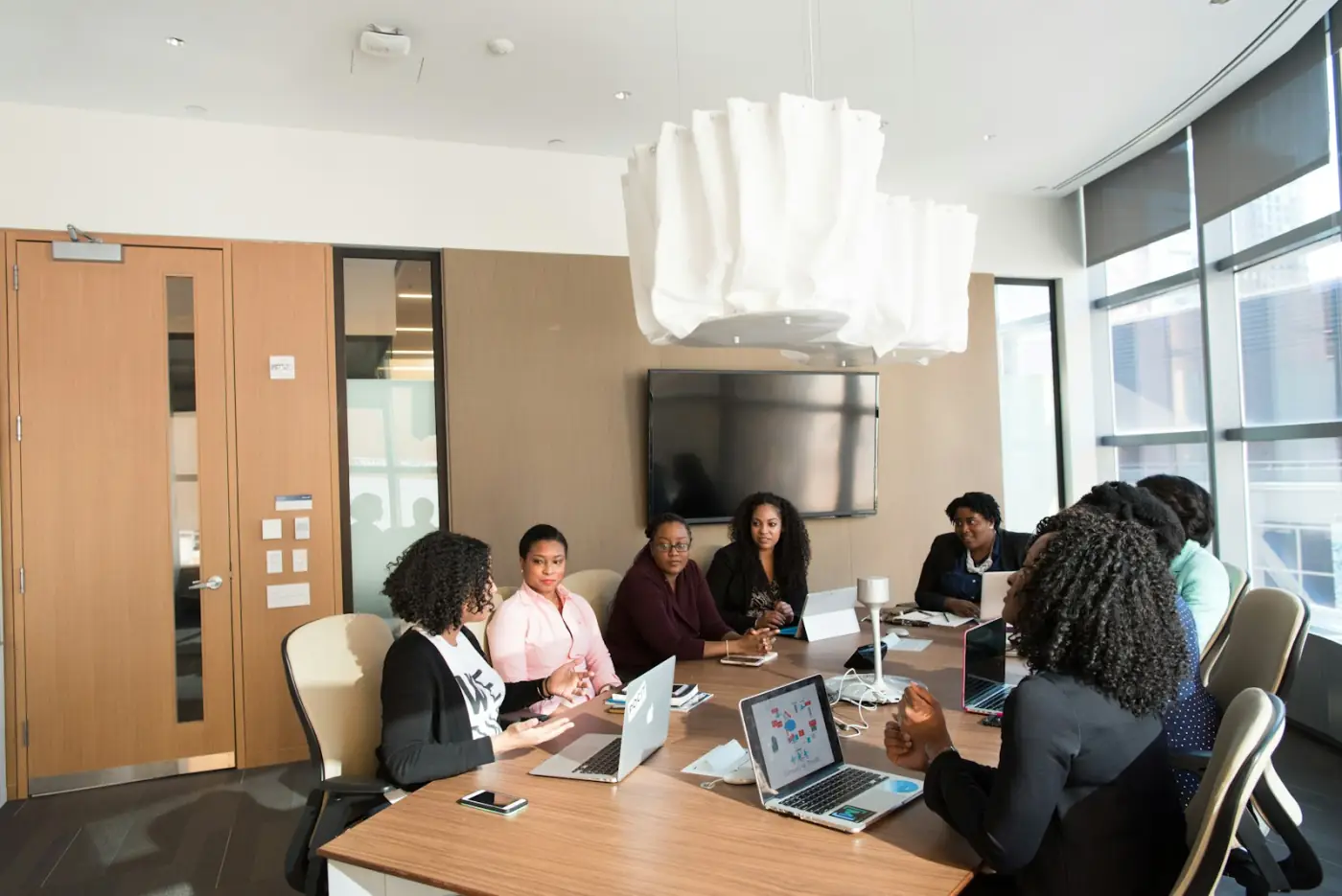 A team of women working on laptops around a meeting-room table