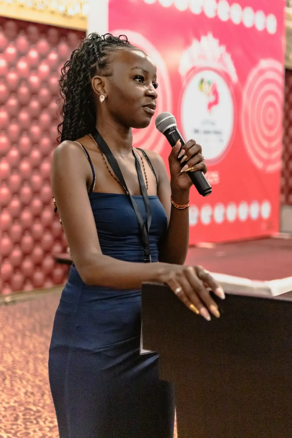 A speaker addresses the audience from the stage, microphone in hand